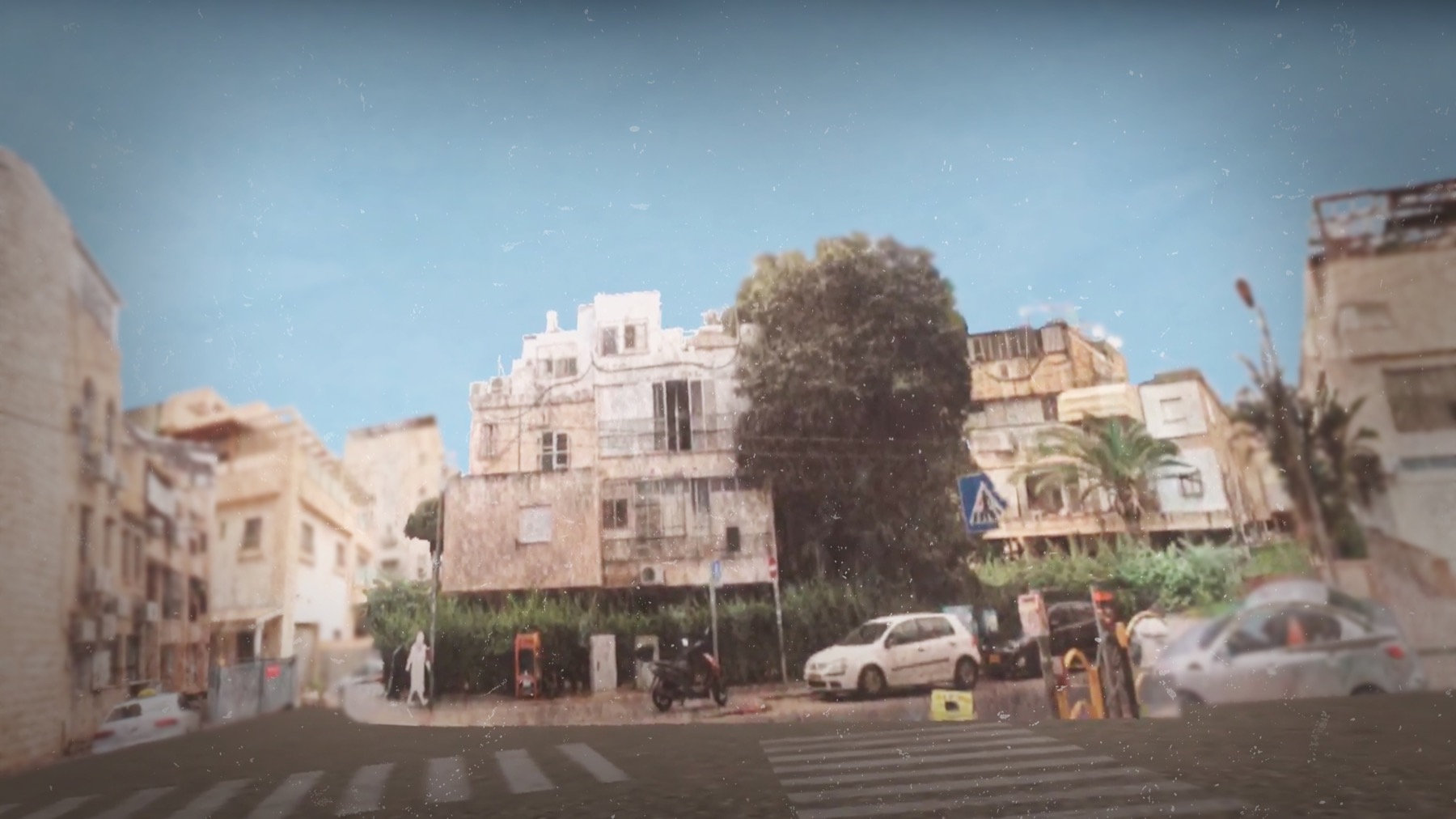 רחוב מגורים בישראל, בנייני דירות לבנים, מכוניות חונות ועצים, תחת שמיים בהירים