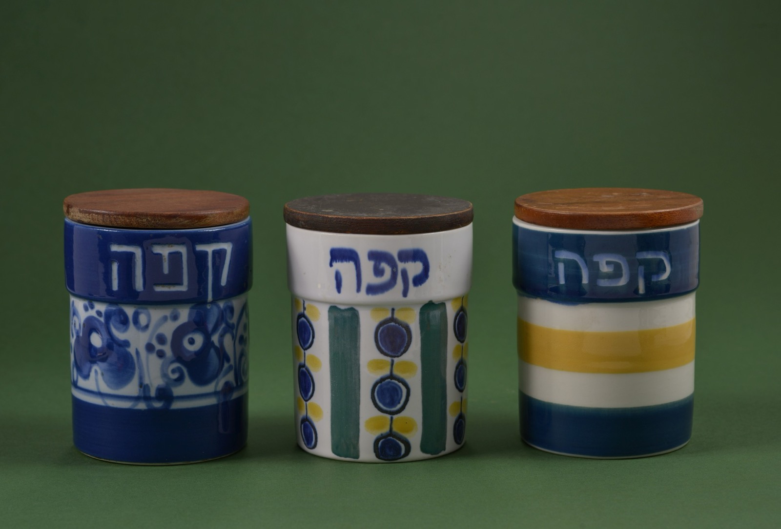 שלוש צנצנות קפה מקרמיקה של לפיד, עם מכסי עץ, ועל כל אחת מצוירת המילה קפה